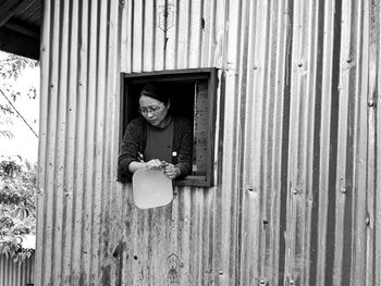 Woman cleaning container while peeking from window