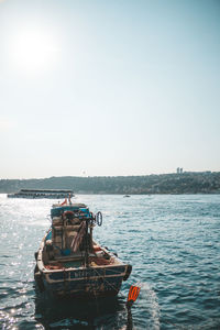 Fishing boat sailing in sea against clear sky