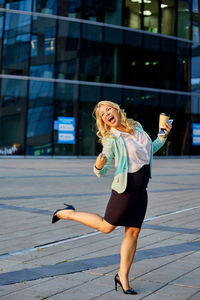 Full length of woman using mobile phone in city