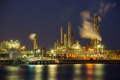 Illuminated factory against sky at night