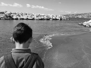 Rear view of boy against sea