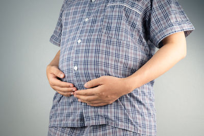 Low section of man standing against white background