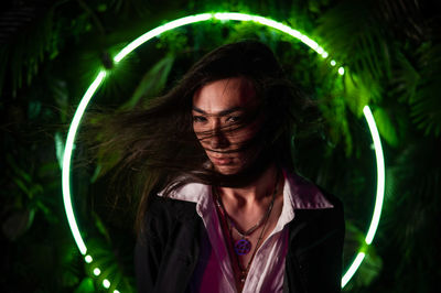 Portrait of young woman standing against plants