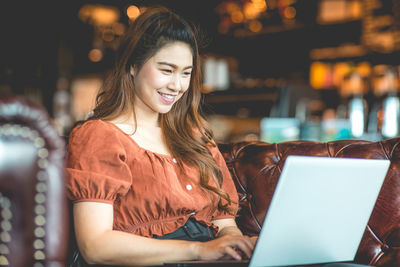 Smiling woman using laptop in cafe