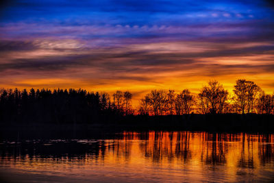 Scenic view of lake against dramatic sky during sunset