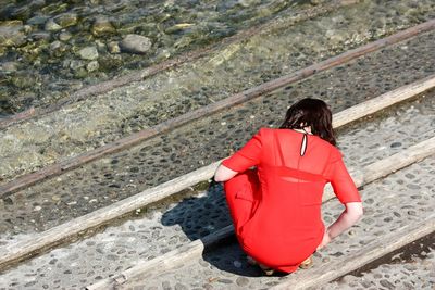 Rear view of a woman crouching outdoors