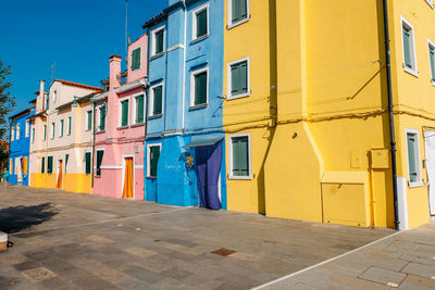 Multi colored residential building by street against blue sky