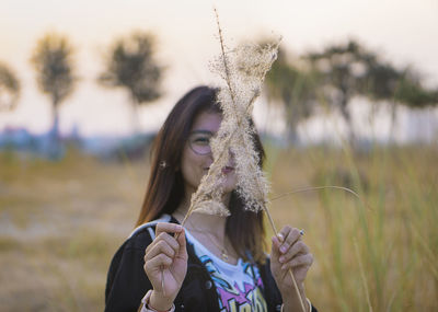 Young woman holding plant against face