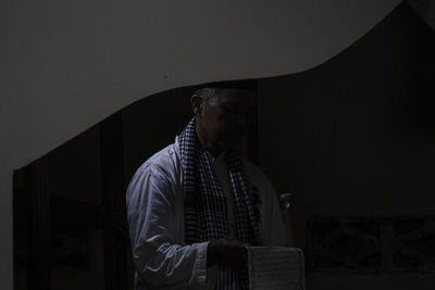 Man standing against wall at night