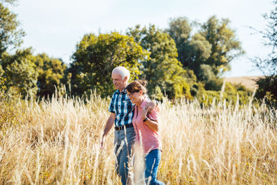 Senior people walking in field against trees