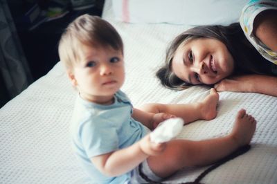 Mom looking at cute baby boy lying on bed at home 