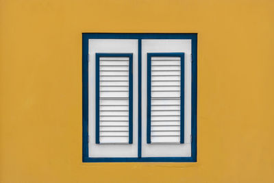Close-up of closed window on yellow wall of building
