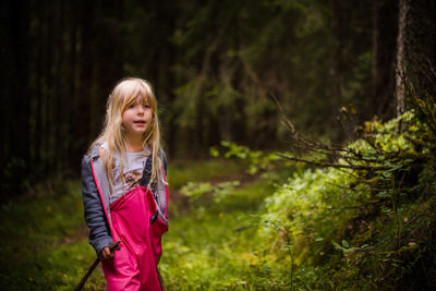 Cute girl standing by plants in forest