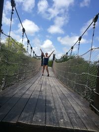 Rear view of women on footbridge against sky