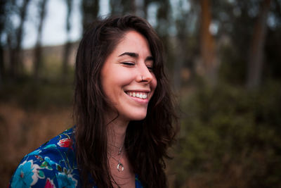 Close-up of smiling young woman with eyes closed in forest