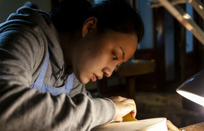 Female craftsman violin maker working on a new violin in the workshop