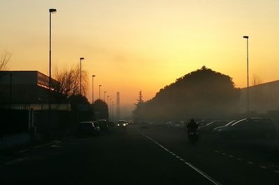 Cars on road against sky during sunset