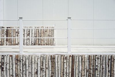 Wooden logs arranged by railing against wall