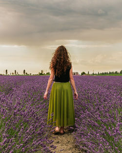 Rear view of woman with umbrella on field against sky