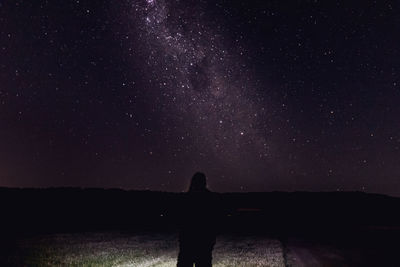 Silhouette man standing against star field in sky at night