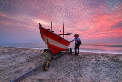 People on beach against sky during sunset