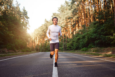 Full length of young man running on road