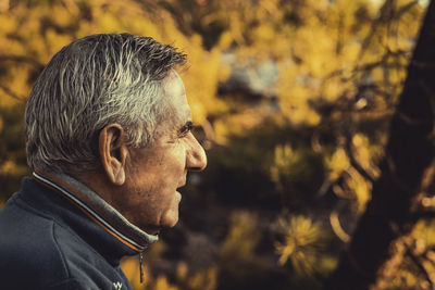 Side view of smiling man looking away during autumn