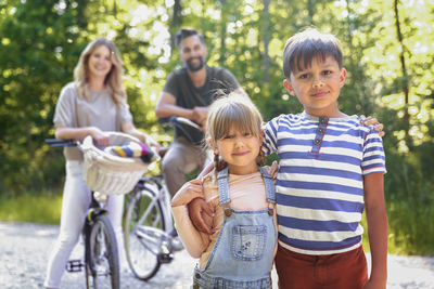 Portrait of happy friends riding bicycles on road