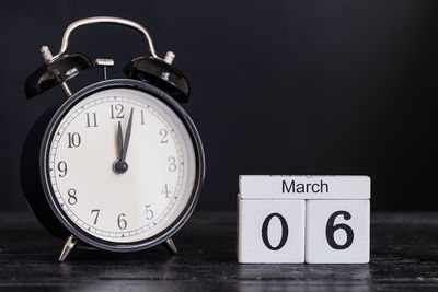 Close-up of clock with calendar on wooden table