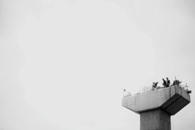 Low angle view of workers on built structure against clear sky