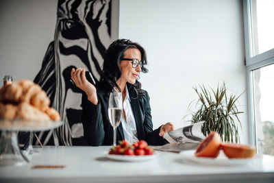 Businesswoman holding mobile phone while sitting in office