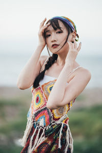 Portrait of young woman standing against sky