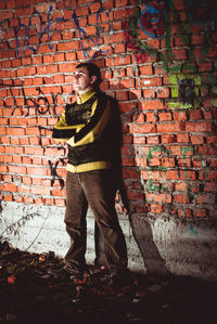 Full length of man standing against brick wall