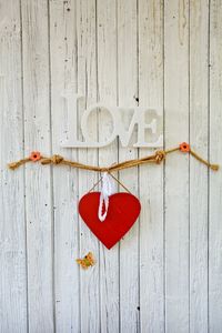 Close-up of heart shape with love text hanging on wood