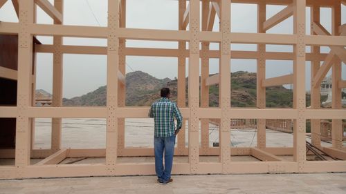 Rear view of man standing against built structure