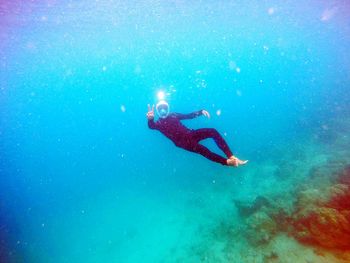 Full length of scuba diver gesturing in sea