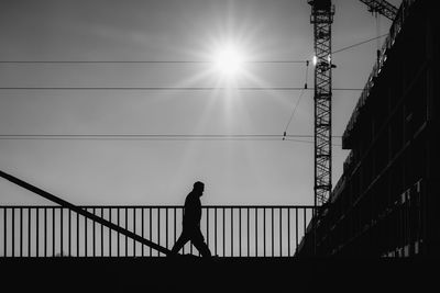 Silhouette man on bridge against sky during sunset