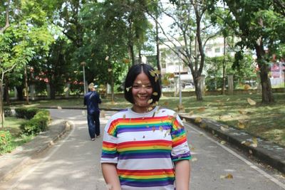 Smiling young woman standing against trees