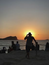 Silhouette people on beach against clear sky during sunset