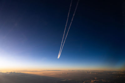 Low angle view of airplane flying against sky during sunset