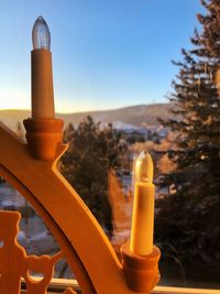 Close-up of lamp on glass against orange sky