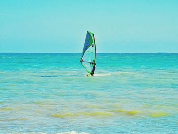 Person paragliding in sea against sky