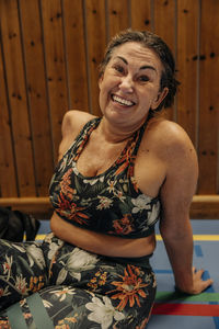 Portrait of happy female athlete resting while sitting at sports court