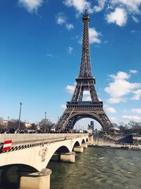 Eiffel tower over river against sky in city