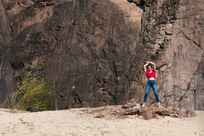 Full length of woman standing on rock at beach