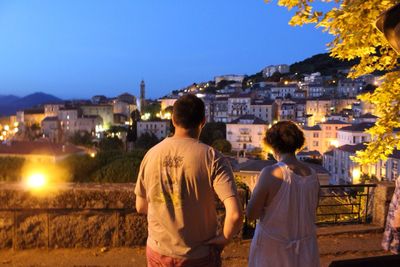 Rear view of man and woman standing by townscape