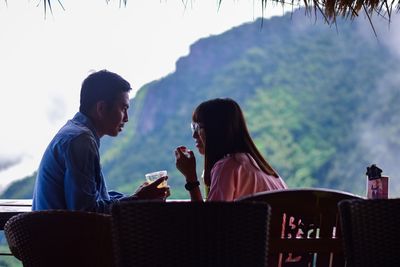 Couple sitting on chair against mountain