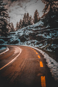 Road amidst trees against sky during winter