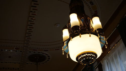 Low angle view of illuminated pendant light hanging in building