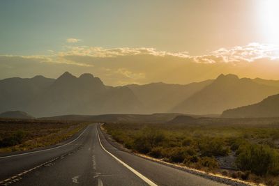 Road leading towards mountains against sky